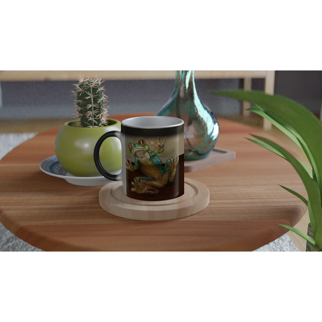Magic color changing 11 oz mug - Toad-ally caffeinated features green and blue tree frog with orange eyes clinging to the side 11oz right view on table with plant and vase