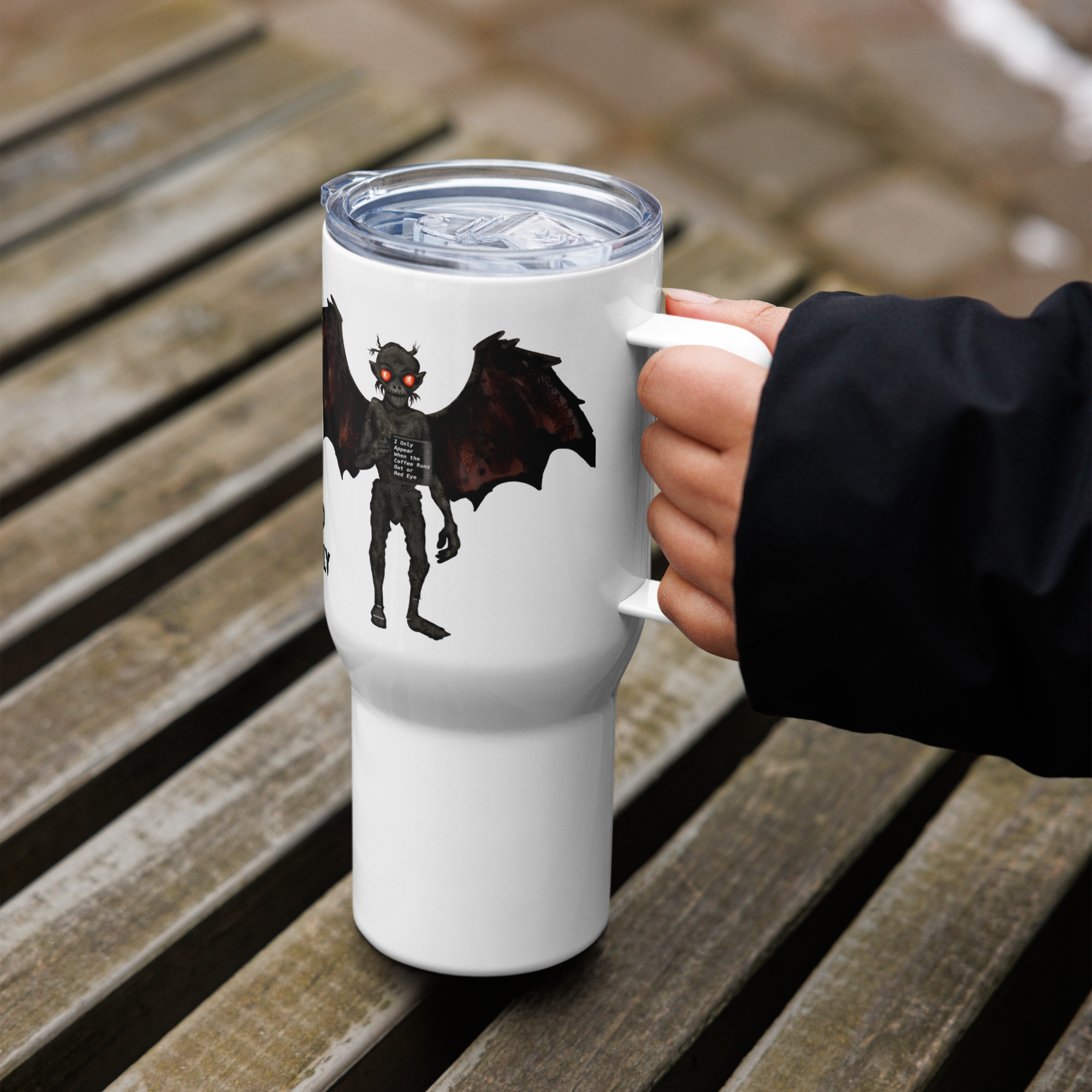 White tumbler with mothman creature design held by a hand on a wooden surface - 25 oz