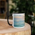 White ceramic mug with black interior featuring a calming ocean sunrise design on a wooden table