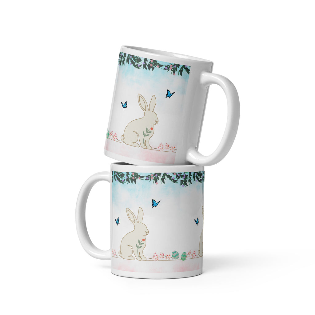 Premium White Ceramic - Bunny and Butterfly Mug -Gentle cream-colored bunny in peaceful garden setting
Blue butterflies fluttering around the scene
Eucalyptus and floral garland border at top
Soft pink cherry blossom accents and pastel Easter eggs at bottom
Soft turquoise sky background with watercolor effect - 11 oz 