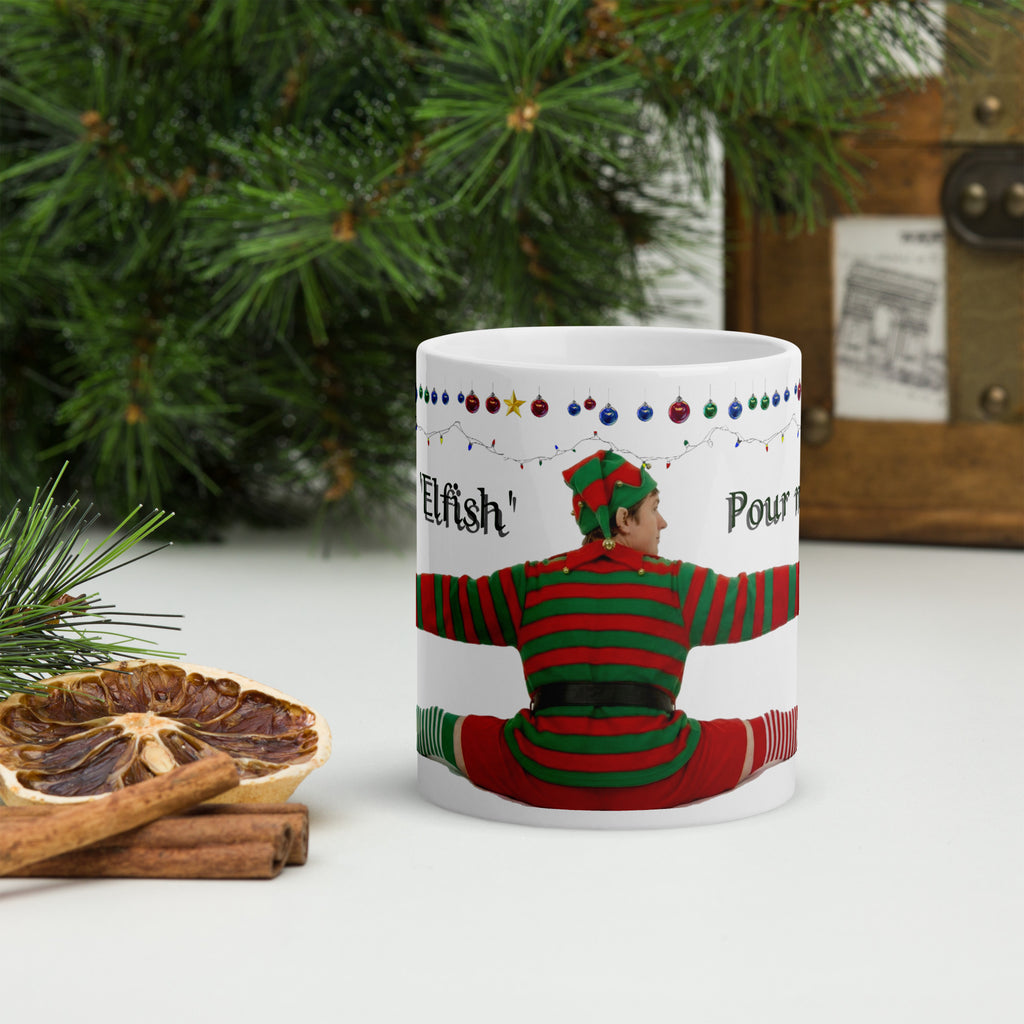 Premium white ceramic - Don't be Elfish - Pour me a cup! - Coffee mug - features cheeky elf dressed in holiday colors hugging the mug with colorful ornaments border at the top- 11 oz front view