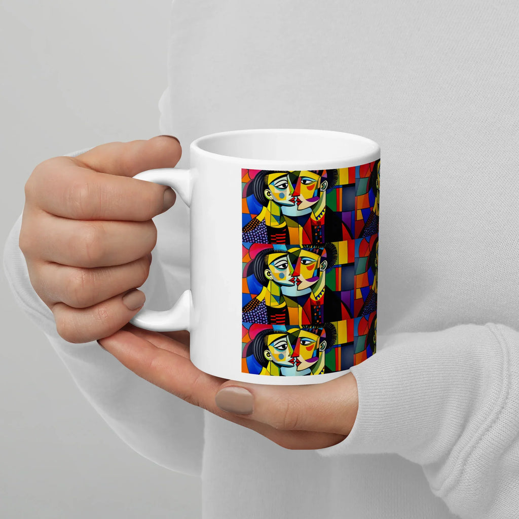 White ceramic mug with vibrant abstract faces and geometric patterns, held in hands