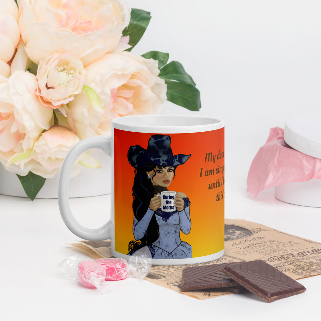 Stunning Premium white ceramic mug features a gorgeous gothic Victorian lady with incredible dark blue floral hat and long flowing hair, pale porcelain skin, and striking features. Dressed in an elegant blue corset-style dress, she holds a mug that says "Curing the Morbs."  11 - oz left view