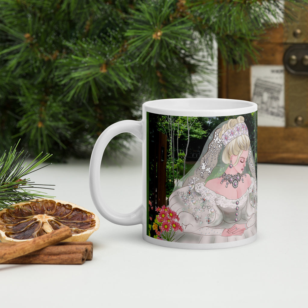 Mug with a decorative design of a bride in a garden setting, placed on a surface with greenery and cinnamon sticks.