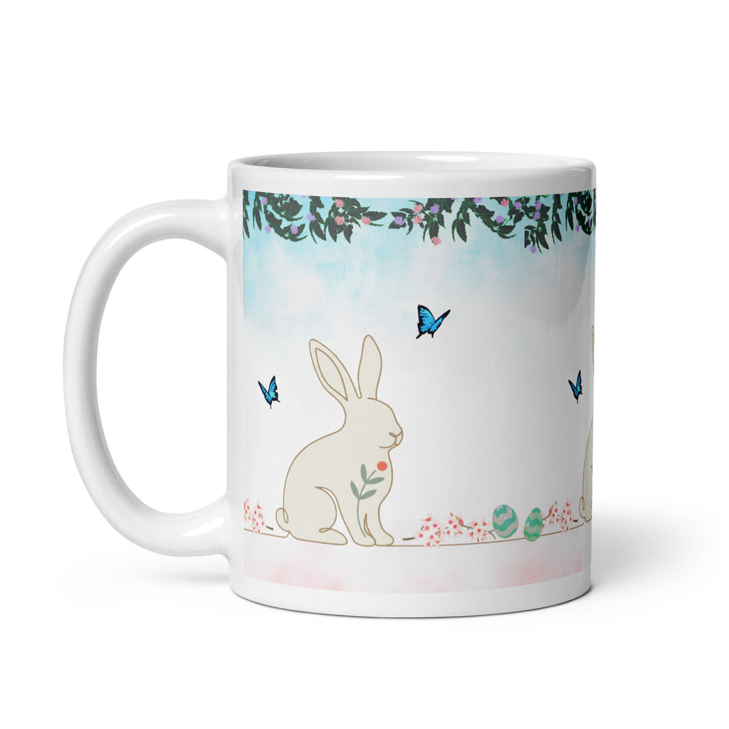 Premium White Ceramic - Bunny and Butterfly Mug -Gentle cream-colored bunny in peaceful garden setting
Blue butterflies fluttering around the scene - Eucalyptus and floral garland border at top - Soft pink cherry blossom accents and pastel Easter eggs at bottom - Soft turquoise sky background with watercolor effect - 11 oz left view