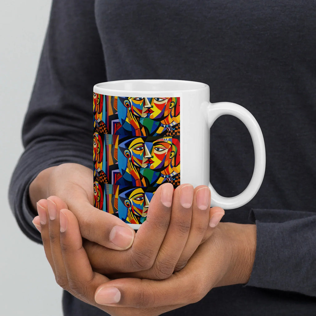 Hands holding a white ceramic mug with colorful abstract faces design