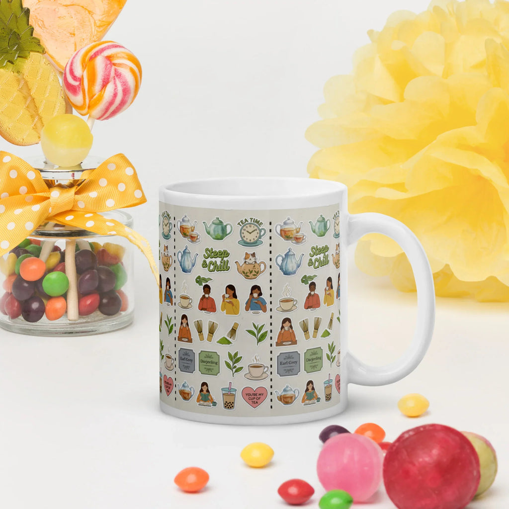 White ceramic mug with colorful tea-themed illustrations, displayed near candies and decor