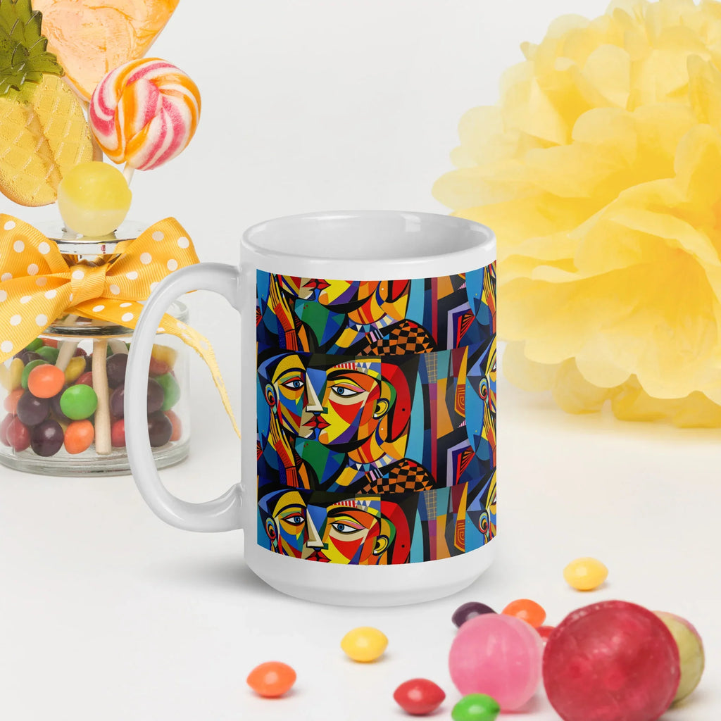 White ceramic mug with colorful abstract faces design, surrounded by candies and yellow decor