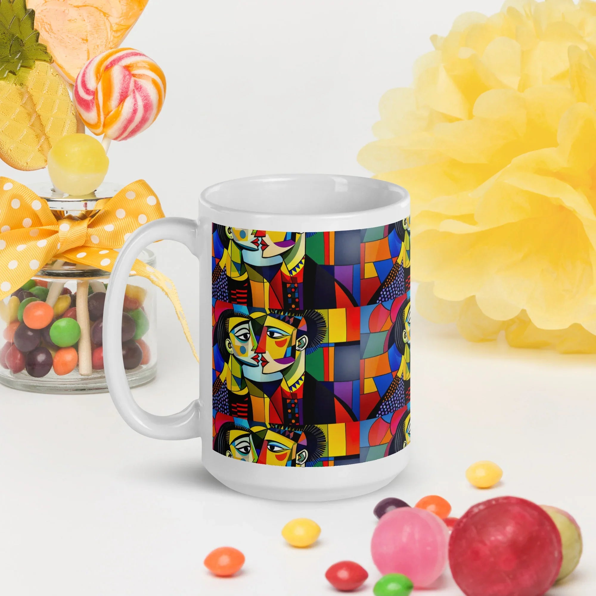 White ceramic mug with vibrant abstract faces and geometric patterns, surrounded by candies