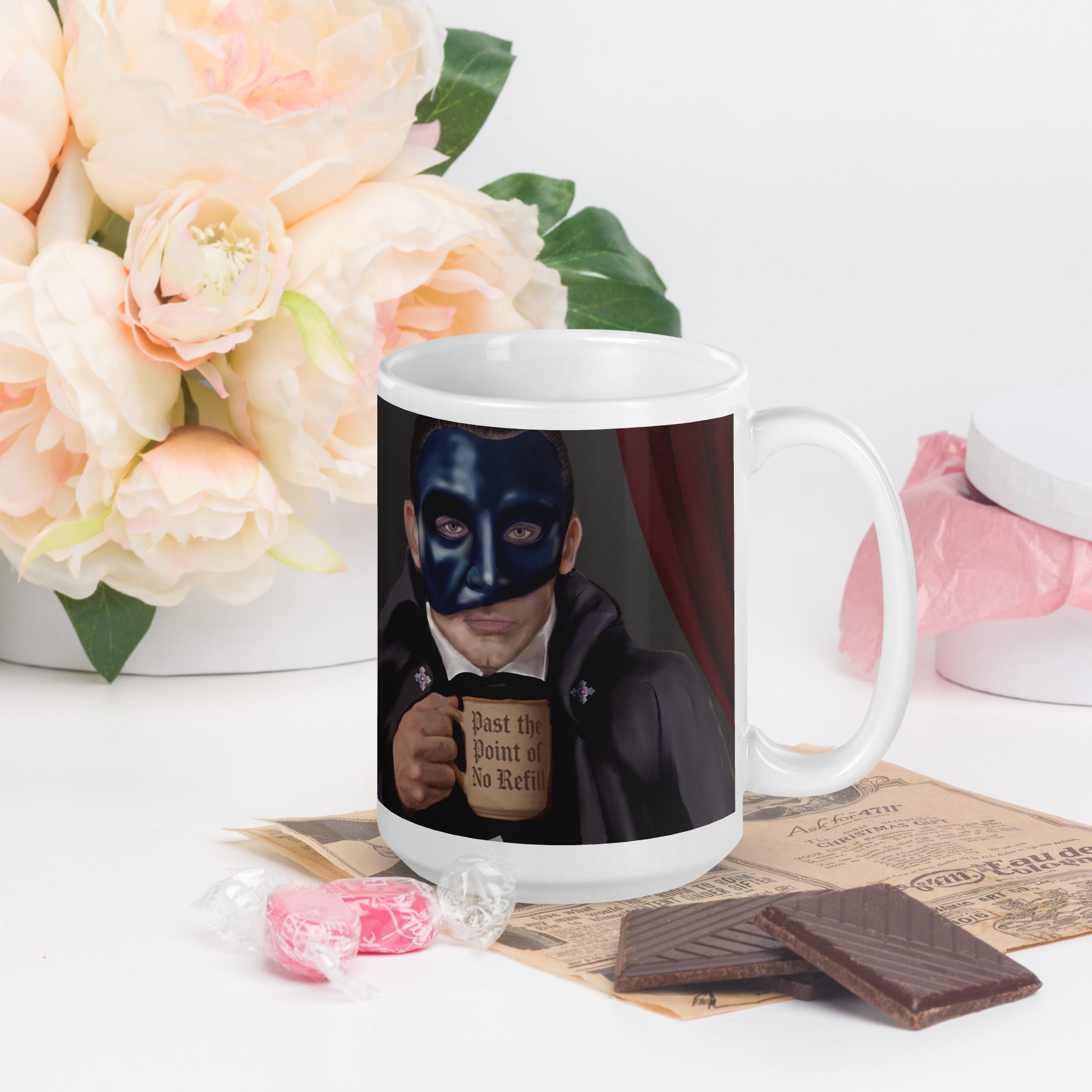 Premium white ceramic - Past the point of No refill - Coffee mug  The Phantom in formal attire with iconic half-mask, clutching "Past the Point of No Refill" mug beneath the golden chandelier and red velvet curtains - 15 oz - right view on a table with flowers and chocolates