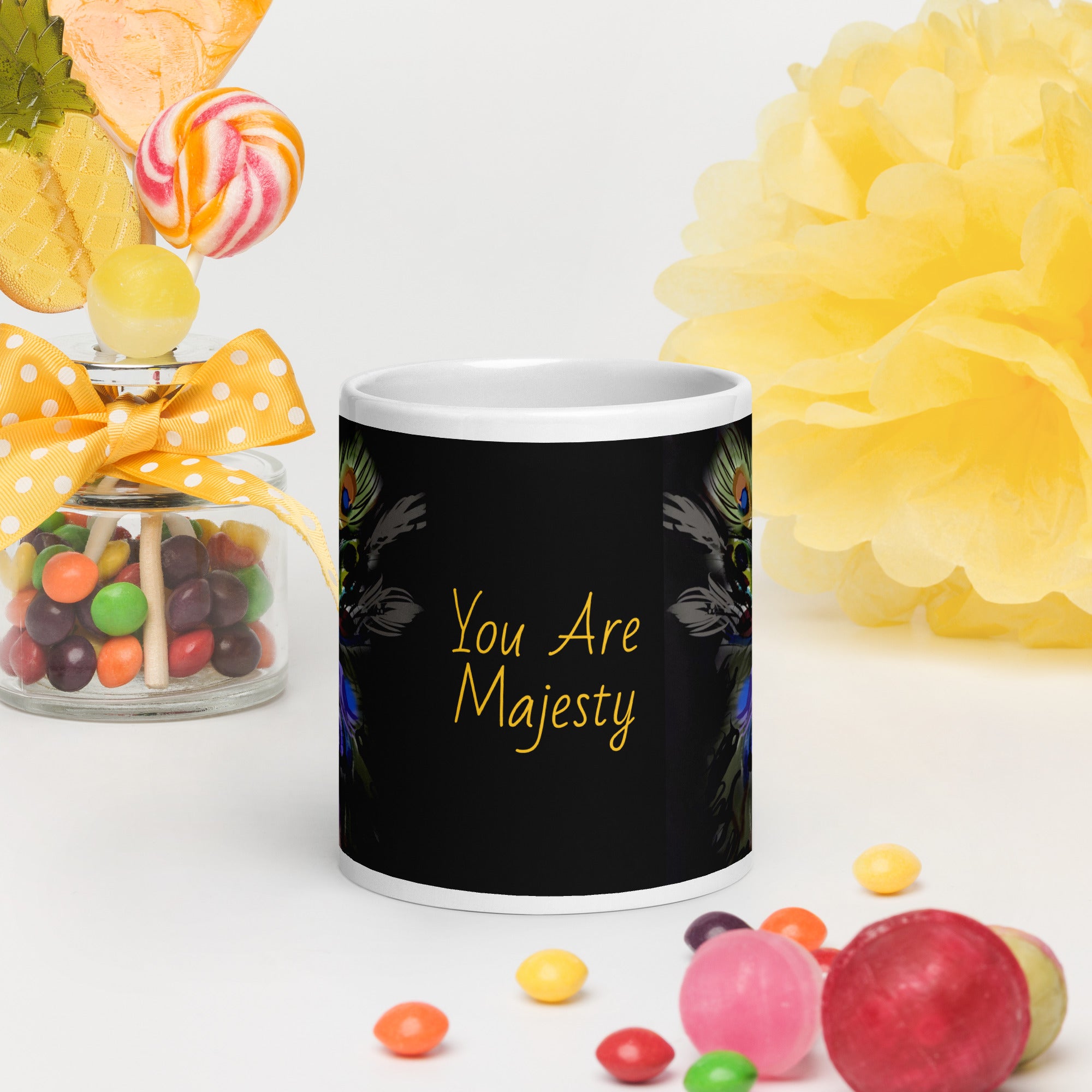 Stunning Premium white ceramic mug features a majestic woman adorned with vibrant peacock feathers, ornate blue and orange face paint, and a regal purple and green costume. With the inspiring message "You Are Majesty, 20 oz front view