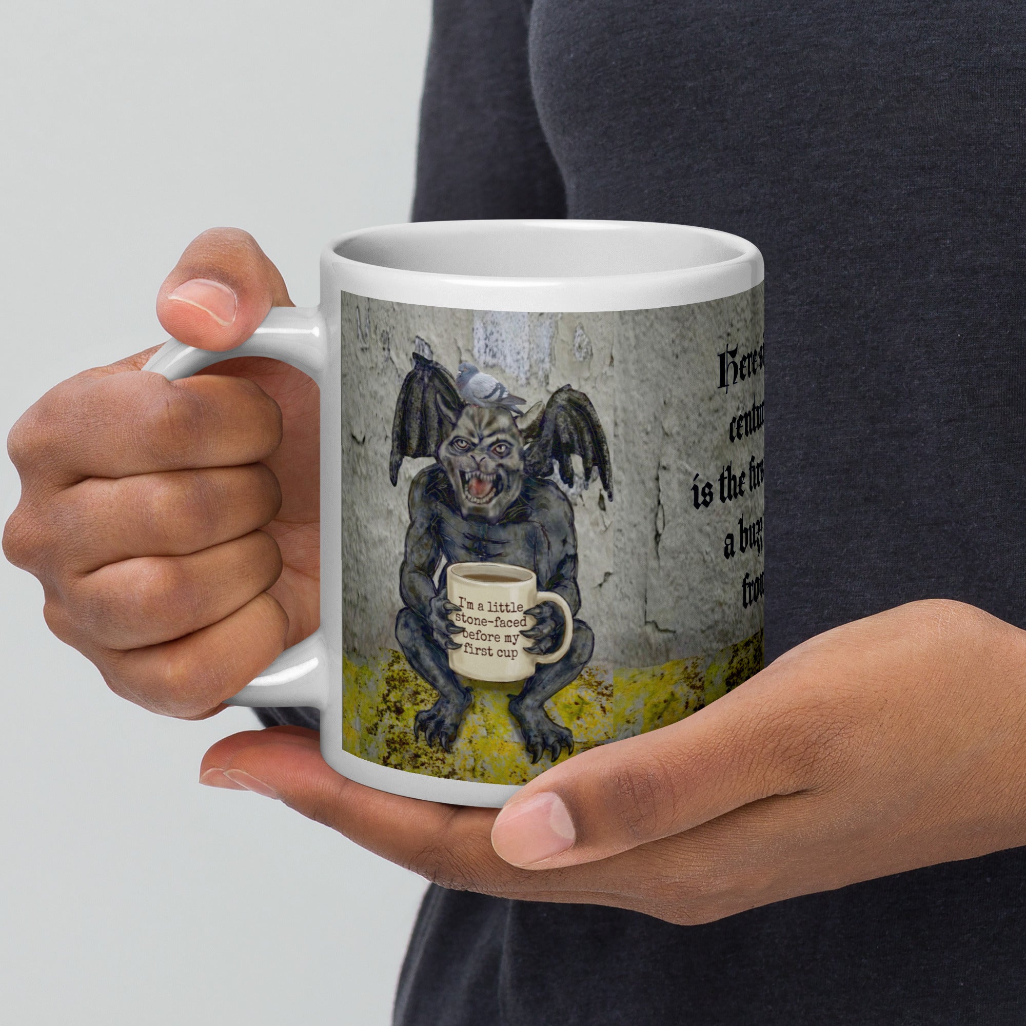 Premium white ceramic Gargoyle mug- Grumpy gargoyle with bat wings and  pigeon on his head holding a coffee mug with "I'm a little stone faced before my first cup" written on it. 20 oz left view