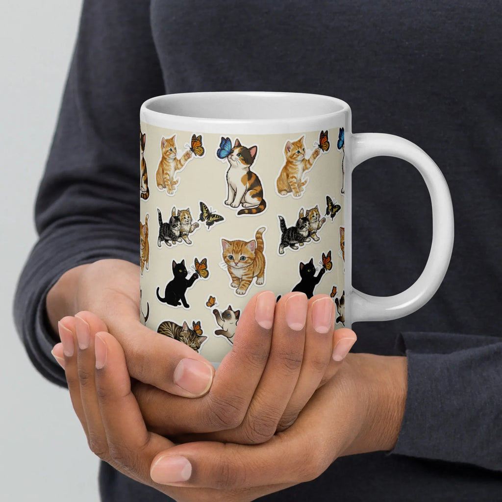 Person holding ceramic mug with cute cat and butterfly pattern, perfect for coffee or tea